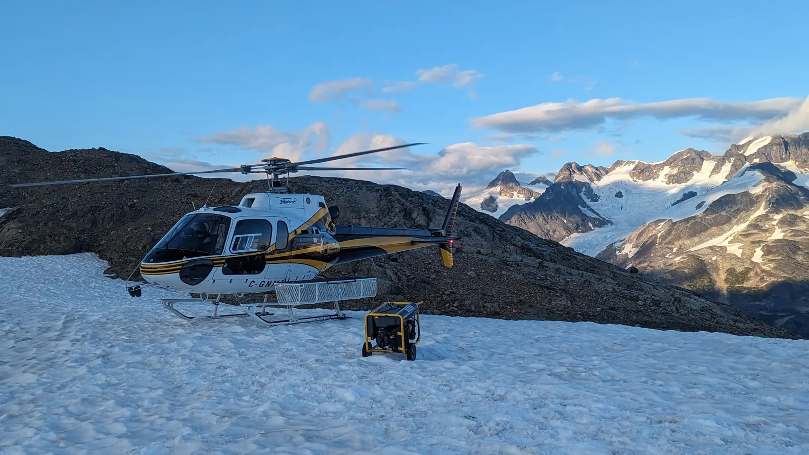 Helicóptero de apoyo y generador sobre nieve durante la inserción de equipo en terreno glaciar de alta montaña