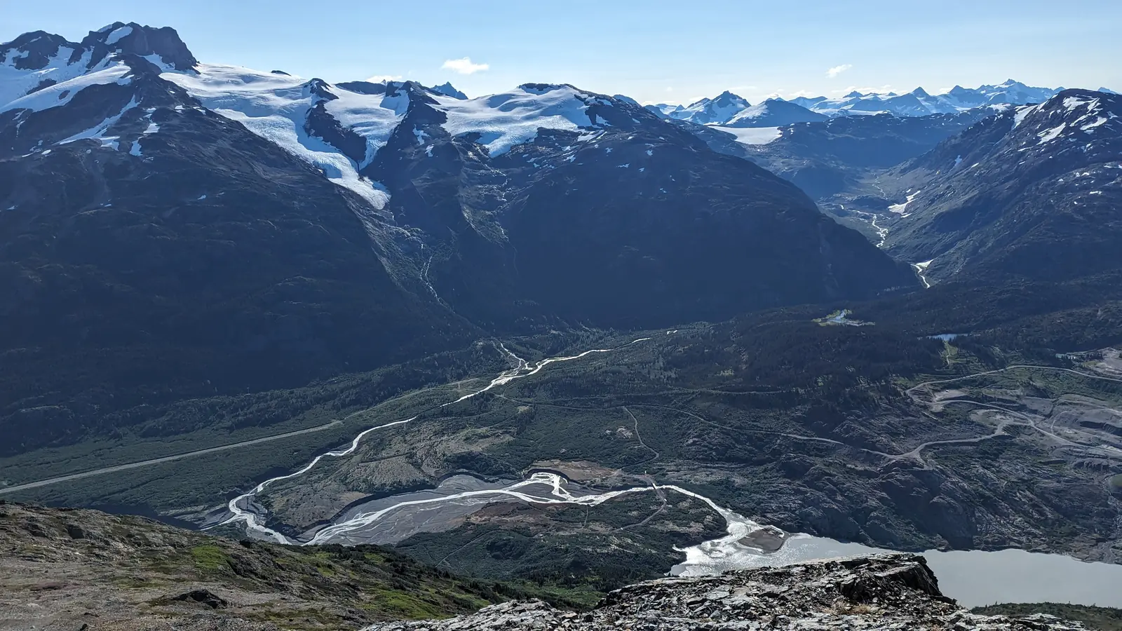 Vista aérea de un valle glaciar con río trenzado entre montañas nevadas